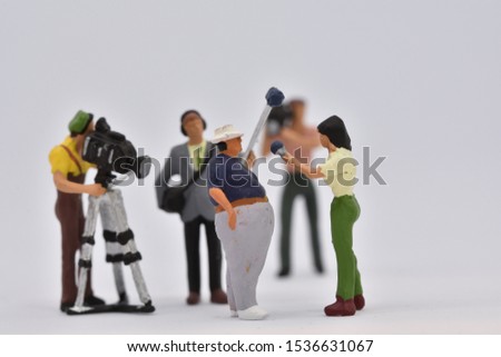 miniature people are discussing in front of a camera crew