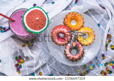Wild berries smoothie with a plate with multicolor cakes with the word fun on it on a white cloth with colored confetti