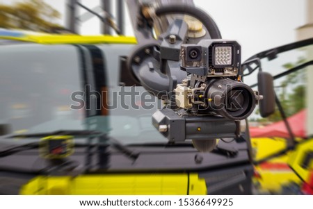 Modern firefighting system mounted on a hydraulic arm of a fire truck - high pressure nozzle with a camera and lighting; blurred background