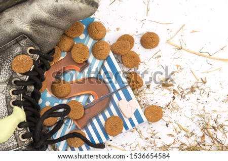 Sinterklaas chocolate letter S at shoe surrounded with gingerbread cookies, sweets and hay residues.