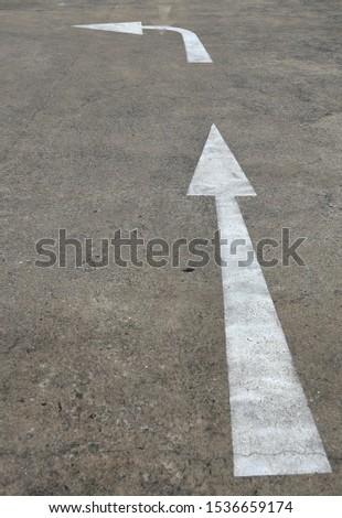 Concrete road with white arrow sign straight and turn left