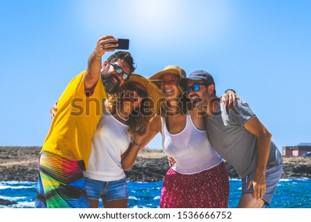 Happy friends taking selfie with smartphone at the beach lighthouse in background Young people having fun together during tropical vacation on an exotic island Youth lifestyle happiness travel concept