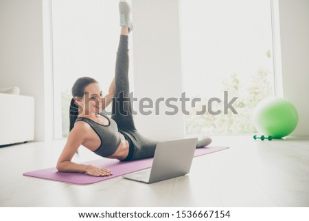 Beautiful positive girl watching sport film movie daily morning regime before working day want be sportive beauty lie on violet mat wearing modern grey panties in studio house like fitness gym Royalty-Free Stock Photo #1536667154