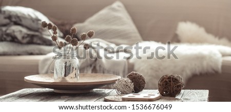 Modern interior of the living room with a sofa and decorative items on the table . Decorative pillows and blankets. Coziness and comfort at home .