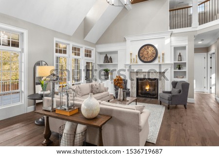 Beautiful living room in new traditional style luxury home. Features vaulted ceilings, fireplace with roaring fire, and elegant furnishings. Royalty-Free Stock Photo #1536719687