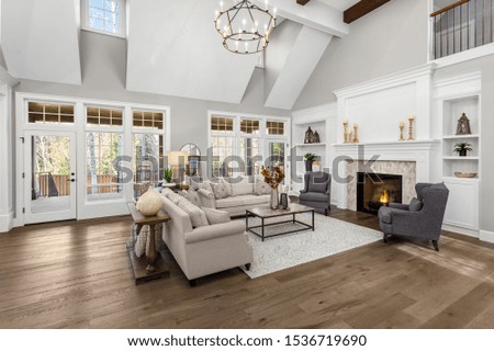 Beautiful living room in new traditional style luxury home. Features vaulted ceilings, fireplace with roaring fire, and elegant furnishings. Royalty-Free Stock Photo #1536719690