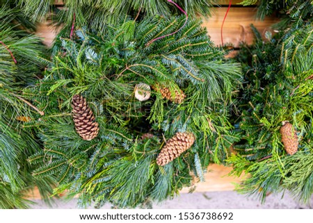 Closeup of green christmas wreaths mistletoe on display in holiday season festive christmas store shop with pine cones