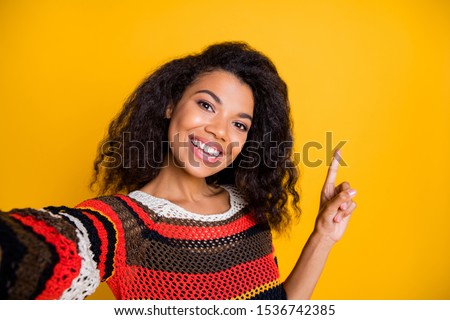 Portrait of positive cheerful dark skin girl promoter have journey excursion make selfie point index finger copyspace follow direct way wear striped trendy shirt isolated shiny color background