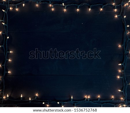 A Christmas tree lights frame over a black wooden surface great for writing text or background Royalty-Free Stock Photo #1536752768