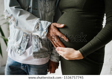 African male holding hands in the belly of a pregnant Russian woman