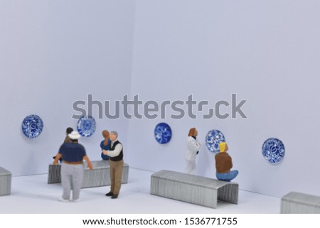 Miniature people are visiting a museum / art gallery with delft blue art