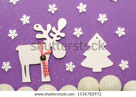 Christmas creative flat handmade picture on top of white cardboard with a deer, Christmas tree and snow on a purple background.