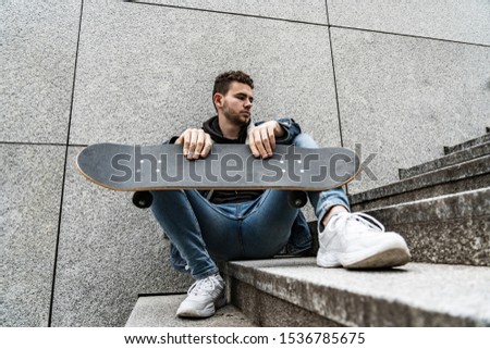 Young an sitting with saketeboard on stairs