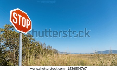 Stop road sign outdoors with fields and blue sky on background.
