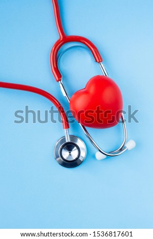 Stethoscope and red heart on blue background. Cardiology and Healthcare concept