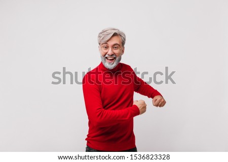 Studio shot of active male model in knitted sweater. Excited grandfather laughing on white background.
