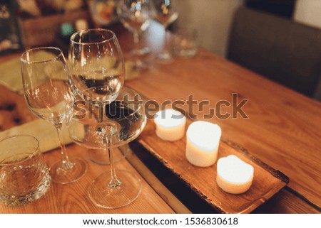 Romantic Wine Glass with Burning Candles and glasses of wine on table in darkness.