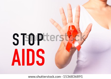 Closeup of female with red ribbon Support HIV AIDS on hand, Stop Aids, World AIDS Day and medicine concept with copy space for use on white background