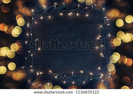 A tree light frame over a black wooden surface surrounded by blurred lights great for background or writing text
