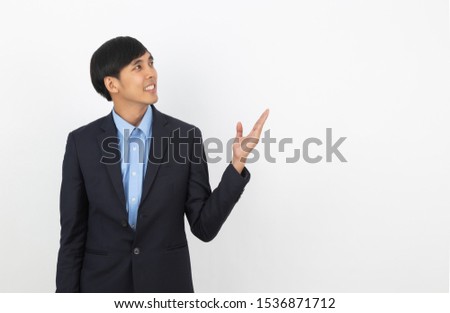 Young asian business man pointing to the side with a hand to present a product or an idea while looking forward isolated on white background.