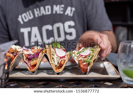 closeup of man reaching for taco outside in summer Royalty-Free Stock Photo #1536877772
