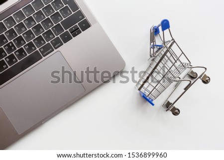 Creative promotion composition for online shopping sale on white background with laptop and grocery cart. Flat lay, top view, overhead, mockup, template