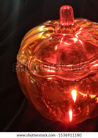 Glass pumpkin with orange twinkle lights on black background