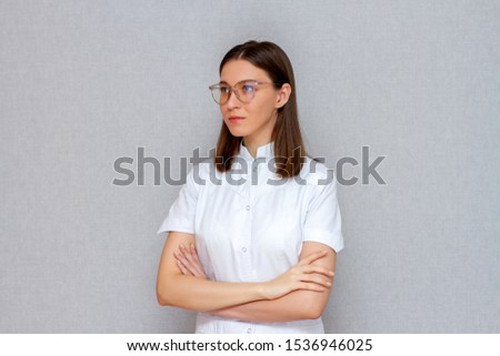 professional nurse girl doctor in a white coat on a gray background