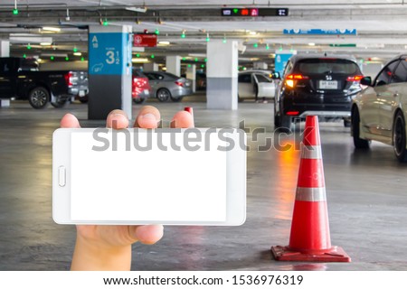 Girl use mobile phone, blur image of parking place in the building as background.