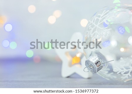 christmas glass ball with snowflakes and wooden star on defocused background with colorful lights