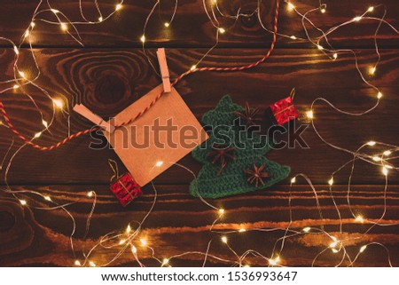 Clothespins with a blank sheet of paper hanging on a background of a background framed from a garland and present, spruce, anise