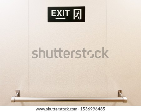 Exit sign on the wall placed above a metallic handle bar