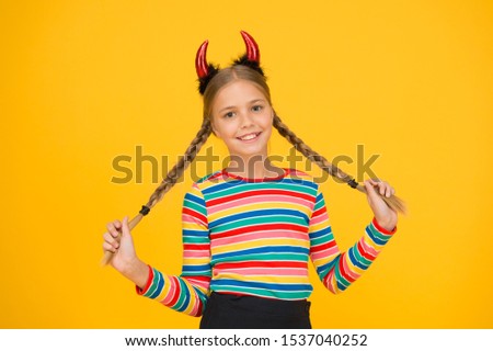 Easy holiday hairdo for long length hair. Halloween child hold long plait hairdo. Small girl wear red devil horns headband with braid hairdo. Hairdo salon. Beauty and hair parlor.