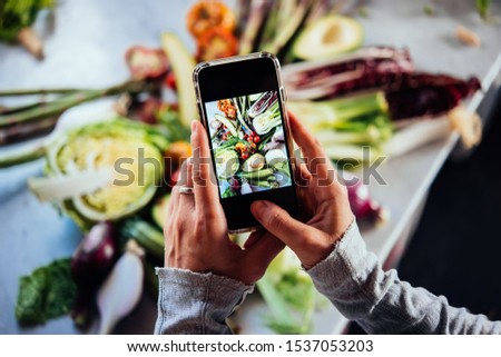 Taking picture of different beautiful vegetables and greens with a mobile phone.
