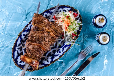 Kebab from mutton ribs skewered on two sticks. Uzbek shish kebab of lamb or veal. Traditionally prepared from mutton with fat tail fat .Uzbek cuisine.