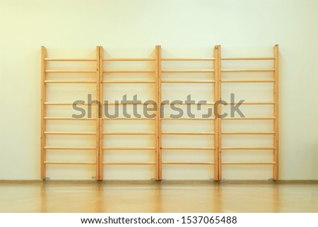 wooden wall bars ladder in big empty gym room of school
