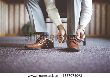 A closeup shot of a male tying his shoes and getting ready for a business meeting