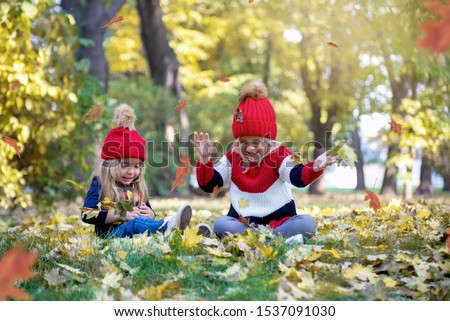 Two sweet little girl in the yellow leaves of autumn