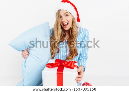 Christmas morning. Happy beautiful young girl, in Christmas pajamas and Santa hat, received a gift on Christmas day, on white background