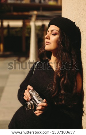 woman in hat holding retro camera and taking picture