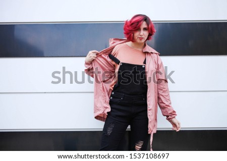 Girl with short pink hair in autumn clothes on black and white background. Copy space.