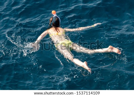 A girl swims in the blue water of the sea.