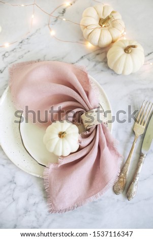 Autumn holidays tabletop decor with white pumpkins and natural linen napkins. Thanksgiving inspiration.