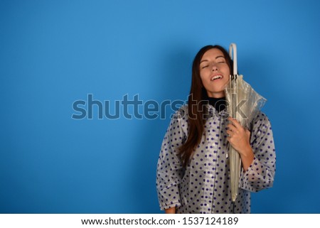 young woman with closed eyes in a raincoat on a blue background