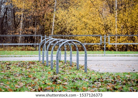 Empty outdoor bike parking in city park. Rainy autumn day. Colored tree leaves