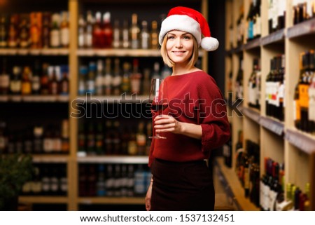 Picture of happy girl in Santa hat with glass in hands of store