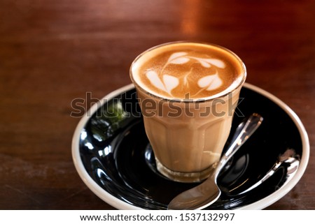 Hot latte in a clear glass on a wooden table