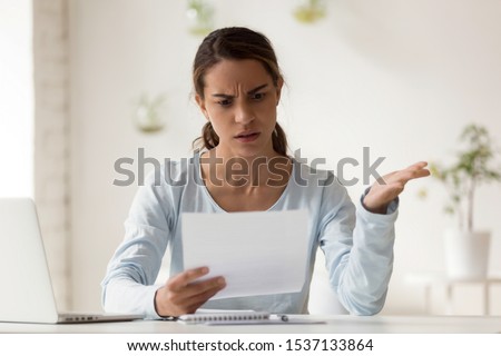Head shot portrait stressed millennial mixed race woman reading paper with bad news. Frowning female employee irritated by dismissal notice. Unhappy young lady disagree with false information. Royalty-Free Stock Photo #1537133864