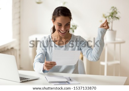 Overjoyed millennial mixed race female worker employee reading letter with good news, celebrating special achievement. Smiling young woman getting bank loan approval or lottery win notification. Royalty-Free Stock Photo #1537133870