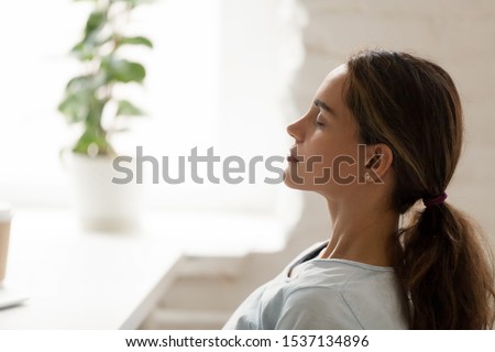 Side view young mixed race woman relaxing with closed eyes at workplace. Peaceful biracial lady freelancer deeply meditating, doing breathing exercises, enjoying break time, reducing stress at office. Royalty-Free Stock Photo #1537134896